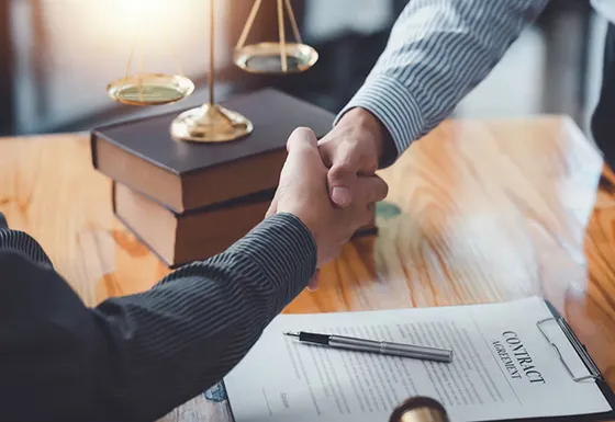 Two professionals shaking hands over a document for bail bond services.