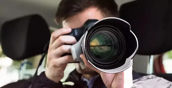 An investigator taking photos near a car, showcasing surveillance skills in private investigation.