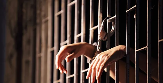 Hand reaching out from behind jail bars symbolizing bail bonds support in Red Bank SC