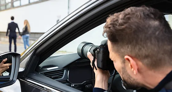 An investigator taking photos near a car, showcasing surveillance skills in private investigation.