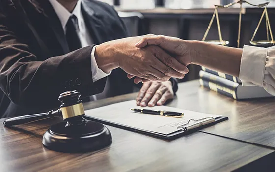A lawyer and client shaking hands with a gavel on the table, symbolizing professional bail bond services in Hopkins, SC.
